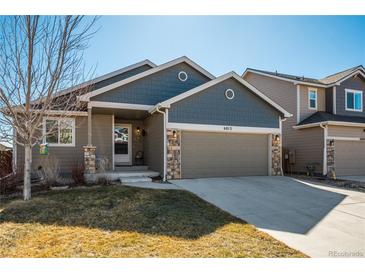 Charming home with a two-car garage, stone accents, and a covered front porch at 6812 Indian Paintbrush St, Frederick, CO 80530