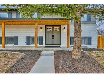 Inviting front entrance with double doors, wooden porch and freshly painted brick at 7017 W 62Nd Pl, Arvada, CO 80003