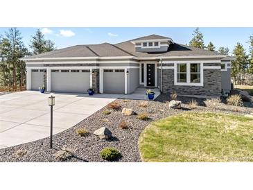 Beautiful home exterior with stone accents, a three-car garage, and drought resistant landscaping at 445 Panoramic Dr, Monument, CO 80132