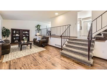 Open living room with hardwood floors, fireplace, and staircase to the upper level at 1348 E Jamison Ave, Centennial, CO 80122