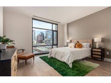 Bright bedroom featuring a large window showcasing the city skyline and comfortable furnishings at 1901 Wazee St # 807, Denver, CO 80202