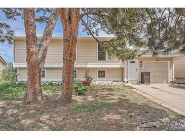 Charming home featuring a well-manicured lawn, mature trees, and a welcoming facade at 15691 E Atlantic Cir, Aurora, CO 80013