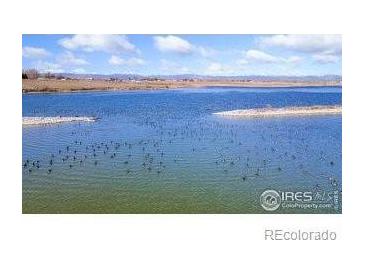 Scenic lake view with abundant wildlife and serene blue waters under a partly cloudy sky at 5425 County Rd 32 # 27, Mead, CO 80504