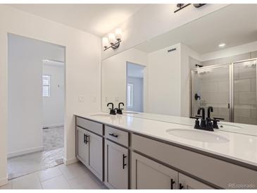 Bright bathroom featuring double vanity with modern fixtures and a glass-enclosed shower, providing a clean and stylish look at 352 N. Geneva St, Aurora, CO 80010