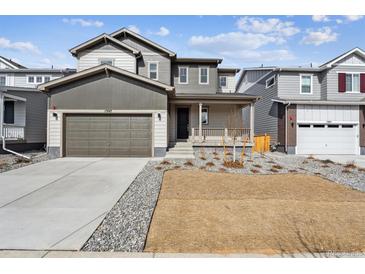 Charming two-story home with a front porch, gray siding, a well-manicured lawn, and an attached two-car garage at 1397 Brookfield Pl, Erie, CO 80026