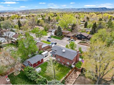 Expansive aerial view of a neighborhood with a brick home, green lawn, mature trees, and mountain views at 2210 Miller St, Lakewood, CO 80215