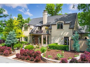 Stunning two-story home with lush landscaping, featuring a charming balcony, elegant architectural details, and mature trees at 6901 E 12Th Ave, Denver, CO 80220