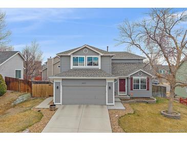 Charming two-story home with a well-manicured lawn, attached two-car garage and a red front door at 13472 Monroe St, Thornton, CO 80241