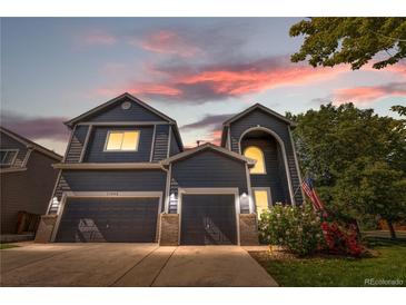 Charming two-story home featuring a well-manicured lawn, two-car garage, and beautiful flowering bushes at 11545 E 119Th Ave, Commerce City, CO 80640