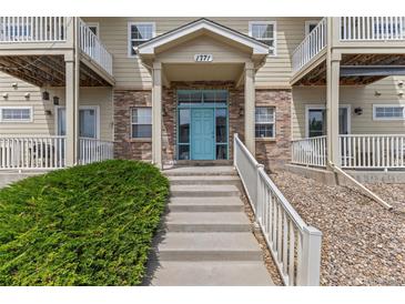 Inviting multi-story condo with brick facade, painted teal front door, and convenient accessible entrance at 1771 W 53Rd Pl # 1, Denver, CO 80221