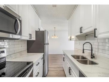 Modern kitchen features white cabinets, stainless steel appliances, and quartz countertops at 7755 E Quincy Ave # 301A2, Denver, CO 80237