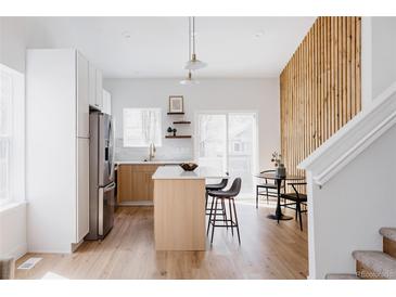 Bright modern kitchen featuring an island with seating, stainless steel appliances, and light wood floors at 4264 Thorndyke Pl, Broomfield, CO 80020