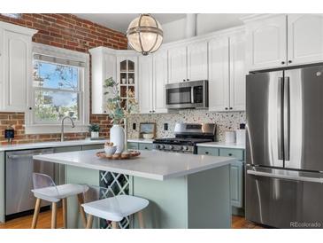 Modern kitchen features stainless appliances, white cabinets, a central island with a wine rack and quartz countertops at 624 E 18Th Ave # 3, Denver, CO 80203
