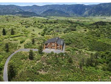 Stunning modern home with wood and glass design, set amongst lush greenery, offering panoramic mountain views at 8821 S Perry Park Rd, Larkspur, CO 80118