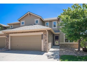 Inviting two-story home with a two car garage, stone accents, manicured lawn, and mature shade tree at 22002 E Irish Dr, Aurora, CO 80016