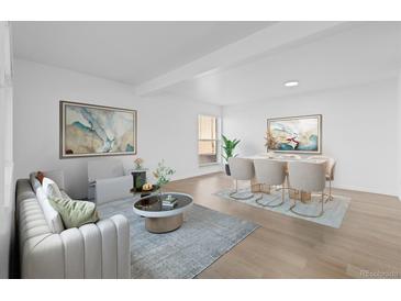Bright living room with modern decor, light wood floors, and an adjacent dining area perfect for entertaining guests at 3663 S Sheridan Blvd # I8, Denver, CO 80235