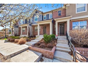 Charming brick townhomes featuring covered front porches, landscaping, and inviting entryways with steps leading to the front doors at 7422 E 7Th Ave # 14, Denver, CO 80230