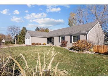 Charming single-story home featuring a well-manicured lawn, gray siding, and a gray tile roof under a blue sky at 7107 E Costilla Dr, Centennial, CO 80112