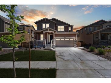 Inviting two-story home featuring a well-manicured lawn and a spacious two-car garage at sunset at 13221 E 110Th Pl, Commerce City, CO 80022