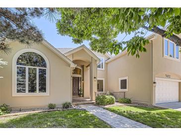 Inviting two-story home with a well-manicured lawn, arched window, and brick pathway at 7452 S Utica St, Littleton, CO 80128