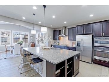 Modern kitchen with large granite island, stainless steel appliances, dark wood cabinets, and pendant lighting at 16021 Williams Pl, Broomfield, CO 80023