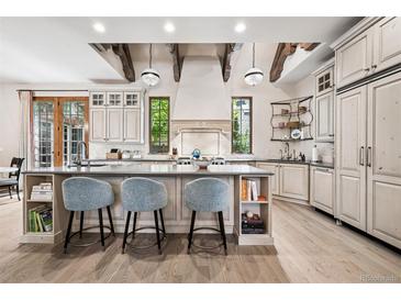 Bright kitchen boasts a large island, pendant lights and beams above an elegant range hood at 2891 E Alameda Ave, Denver, CO 80209