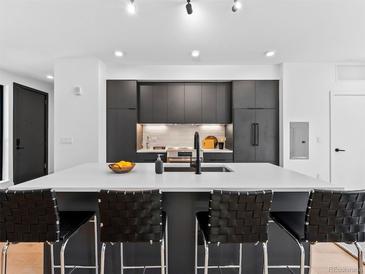 Modern kitchen features a spacious island with seating, sleek black cabinetry, and stainless steel appliances at 1601 Park Ave # 212, Denver, CO 80218