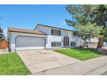 Split level home featuring a two car garage, front lawn and mature trees at 9135 W Maplewood Ave, Littleton, CO 80123