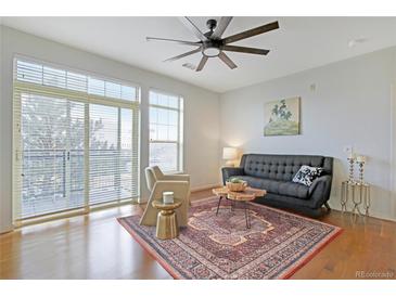 Bright living room featuring large windows, hardwood floors, ceiling fan, and comfortable seating arrangement at 13456 Via Varra # 211, Broomfield, CO 80020