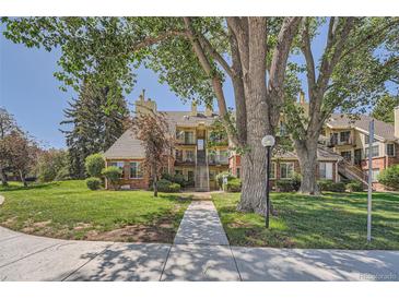 Inviting multi-level condo with landscaped grounds, mature trees, and a sidewalk leading to the entrance at 13704 E Lehigh Ave # D, Aurora, CO 80014