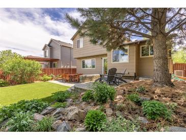 Landscaped backyard featuring a patio with outdoor seating and artificial turf at 2587 Foothills Canyon Ct, Highlands Ranch, CO 80129