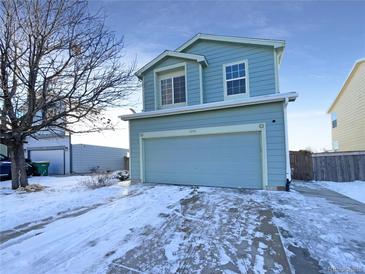 Two-story house with light blue siding, attached garage, and snowy front yard at 1090 Quail Cir, Brighton, CO 80601