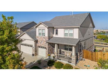 Charming two-story home featuring a welcoming front porch, stone accents, and an attached three-car garage at 6577 S Kewaunee Way, Aurora, CO 80016