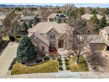 Beautiful brick home featuring professional landscaping and a large front yard, with scenic mountain views in the background at 7425 S Utica St, Littleton, CO 80128