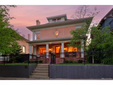 Stately two-story home with a brick facade, covered porch with columns, and well-maintained front yard at dusk at 747 N Downing St, Denver, CO 80218
