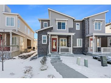 Two-story townhome with gray siding, red door, and snow-covered walkway at 23527 E 5Th Pl, Aurora, CO 80018