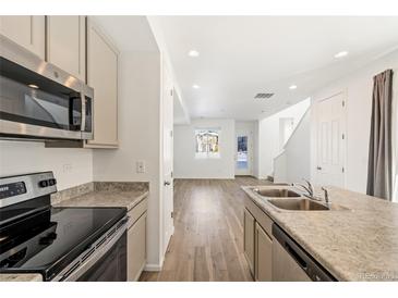 Bright kitchen features stainless steel appliances, granite countertops, and seamless flow to dining and living spaces at 23527 E 5Th Pl, Aurora, CO 80018