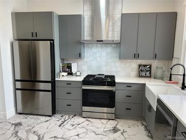 A modern kitchen featuring gray cabinets, stainless steel appliances and a farmhouse sink at 69 W Cedar Ave, Denver, CO 80223