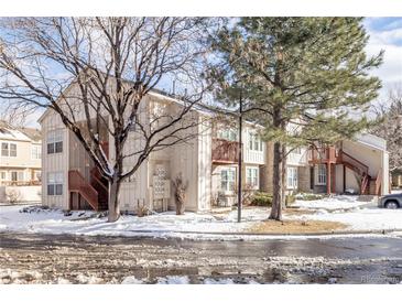 A beautiful, two-story condo with wood stairs, covered balconies, and a snowy yard at 1128 S Ventura Cir # B, Aurora, CO 80017