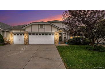 Charming home featuring a three car garage, brick accents, well-maintained landscaping, and a beautiful sky at dusk at 22778 E Alamo Ln, Aurora, CO 80015
