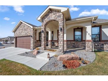 Charming home featuring a stone archway entry, beautiful stone accents and a professionally landscaped yard at 156 Chapel Hill Cir, Brighton, CO 80601