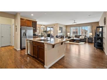 Open kitchen featuring stainless steel appliances, granite counters, and hardwood floors adjacent to living area at 9382 Pike Way, Arvada, CO 80007