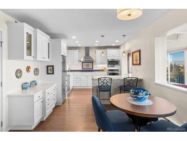Bright kitchen features white cabinetry, stainless steel appliances, and a breakfast nook with scenic views at 1200 N Humboldt St # 1003, Denver, CO 80218