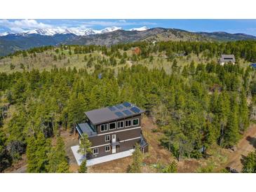 Stunning exterior with solar panels amidst lush forest and mountain views in an elevated setting at 586 Alpine Way, Idaho Springs, CO 80452