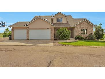 Inviting two-story home featuring a three-car garage and mature landscaping at 14825 Almstead St, Hudson, CO 80642