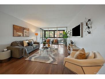 Bright living room with hardwood floors, neutral decor, balcony access, and comfortable seating arrangements at 1050 N Corona St # 202, Denver, CO 80218