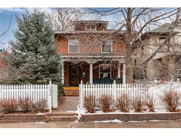 Charming two-story brick home with a covered porch and white picket fence at 1614 Gaylord St, Denver, CO 80206