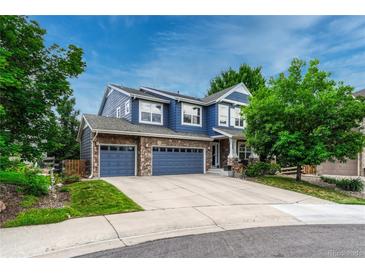 Charming blue two-story home featuring a stone accented three-car garage and a well-manicured lawn at 4688 Cedar Glen Pl, Castle Rock, CO 80109