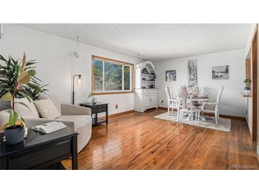 Bright dining area features hardwood floors, a large window, and elegant furnishings at 10983 W Exposition Pl, Lakewood, CO 80226