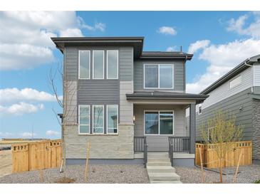 Stylish two-story home with gray siding, stone accents, and a welcoming front porch at 21091 E 63Rd Dr, Aurora, CO 80019